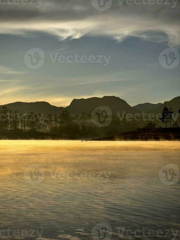 Misty Morning on Green Hill with Reflection in Calm River photo