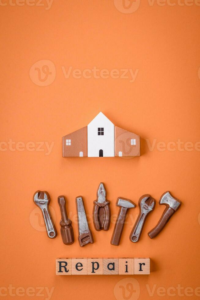 Repair or home improvement tools and a house model on a plain background photo