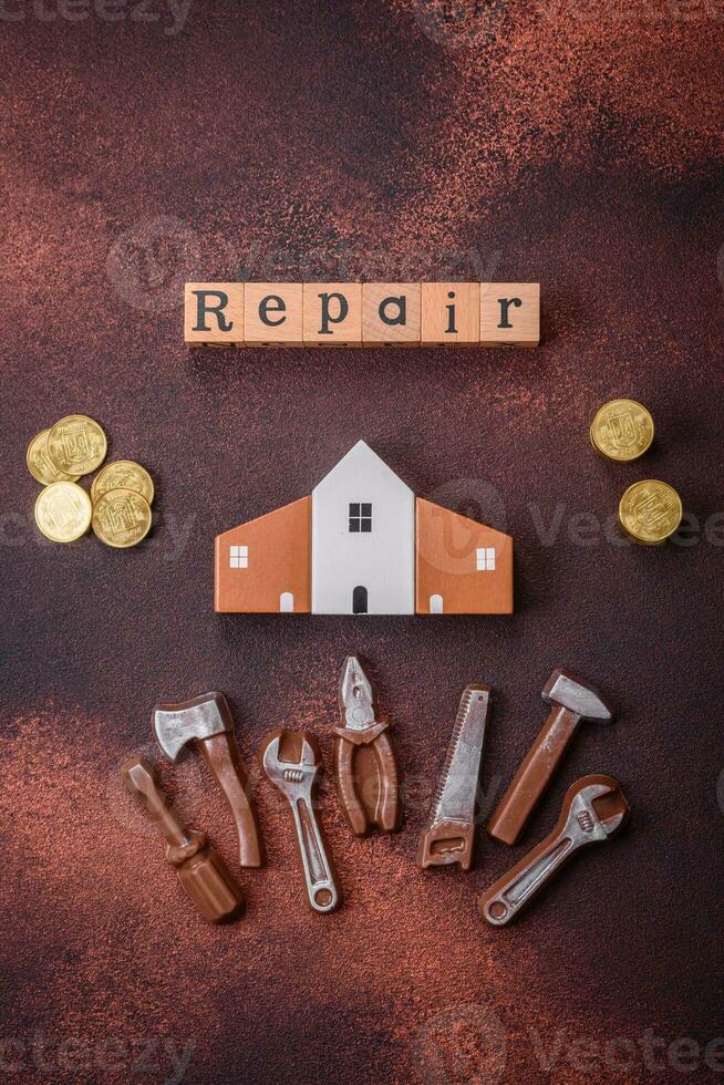 Repair or home improvement tools and a house model on a plain background photo