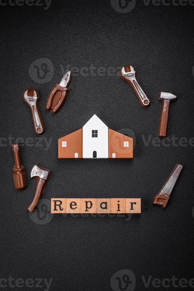 Repair or home improvement tools and a house model on a plain background photo