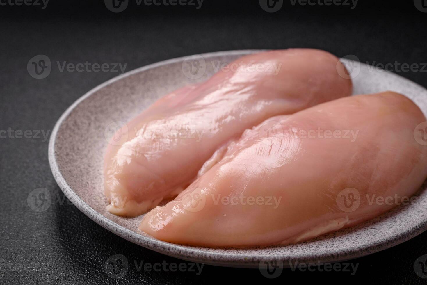 Fresh chicken fillet on a dark concrete table with spices and herbs photo