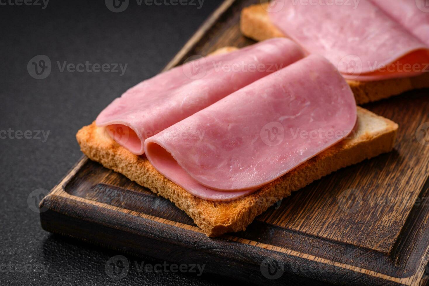 Delicious sandwich with toast bread, ham, tomatoes, salt and spices photo