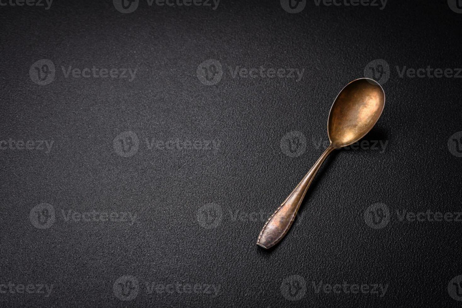 Empty metal spoon on dark textured concrete background photo