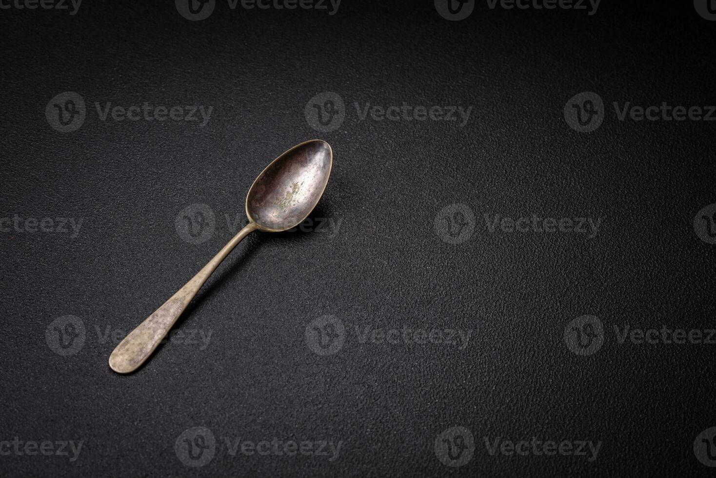 Empty metal spoon on dark textured concrete background photo
