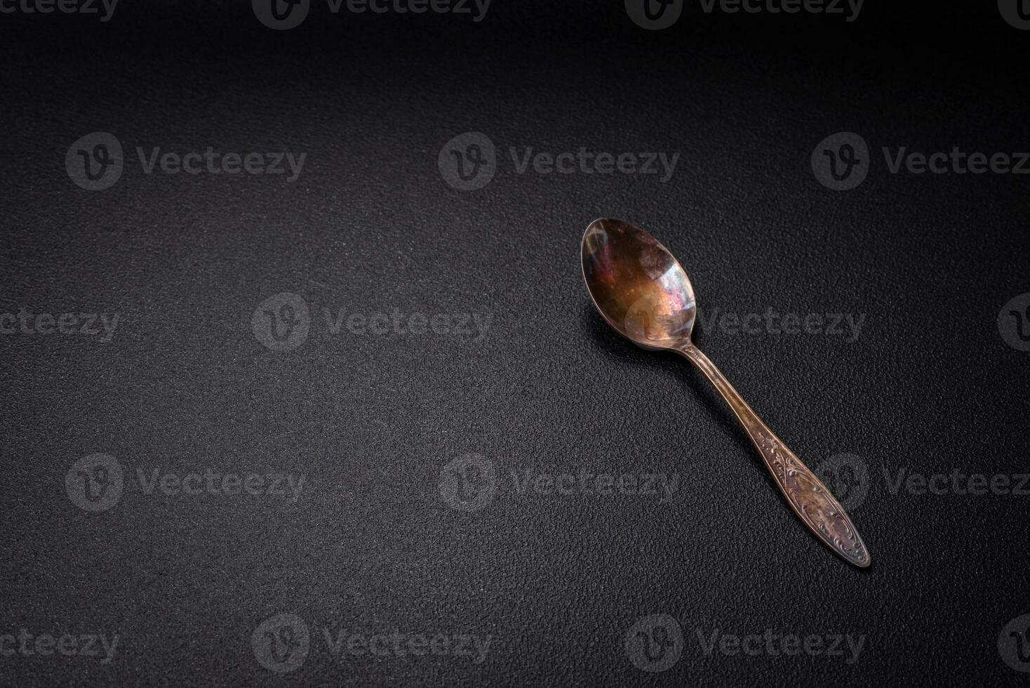 Empty metal spoon on dark textured concrete background photo