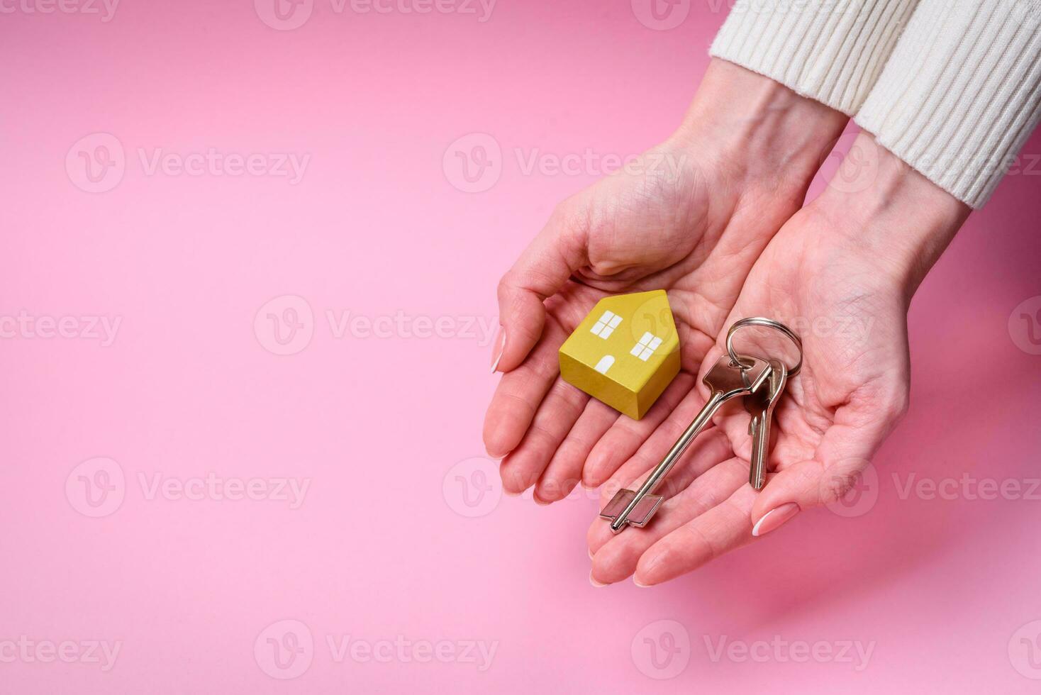 Female hands, a small wooden house and keys as an idea for investing in your own home and achieving the goal of buying real estate photo