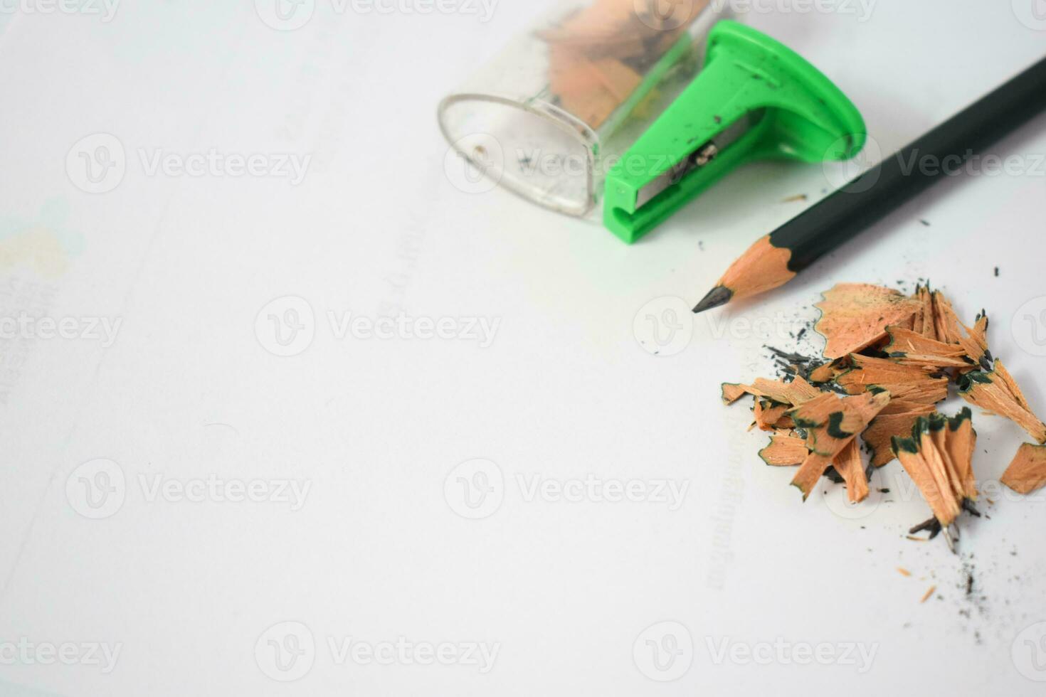 green pencil sharpener and dark green pencils, pencil shavings on white background photo