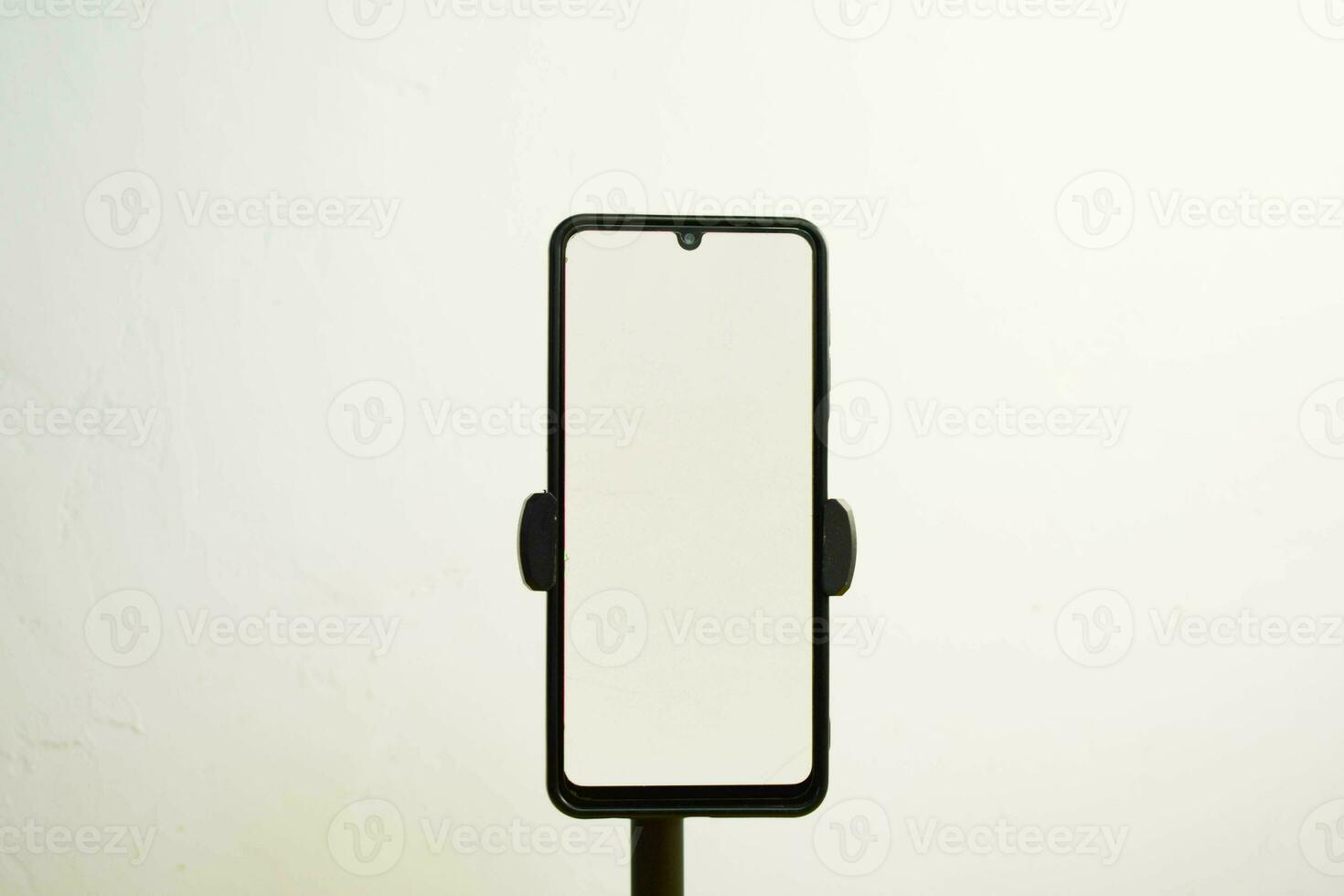 Portrait phone with white screen fixed to tripod on white background, for mockup design. photo