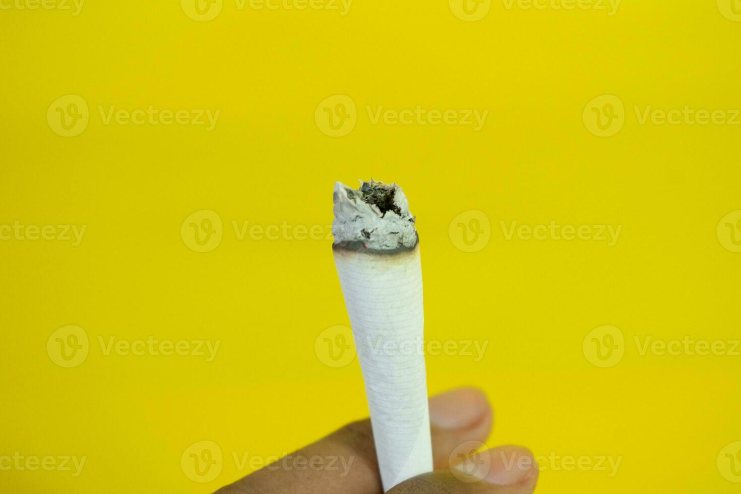 A man hand holds a handmade cigarette on yellow background photo