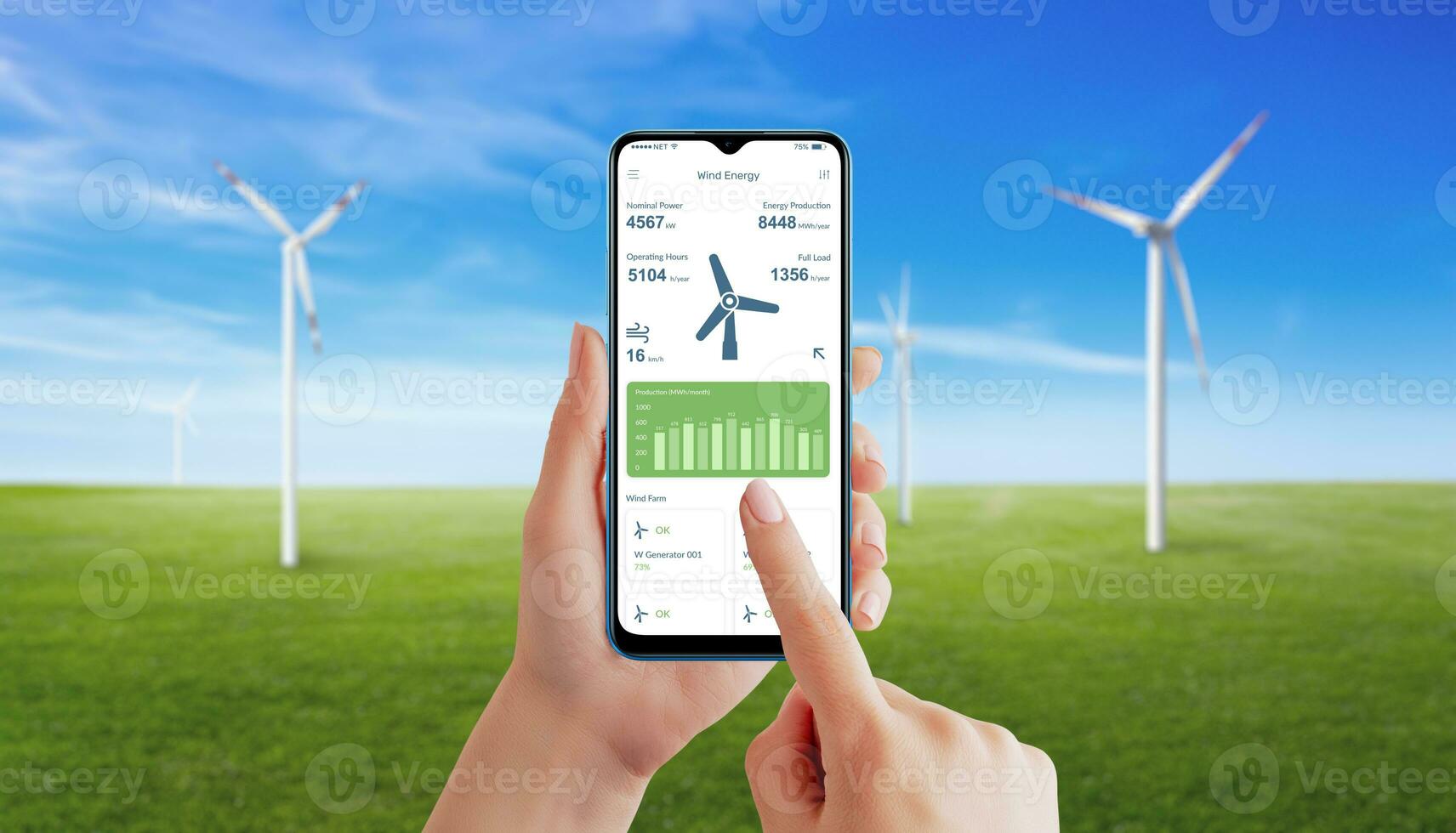 Hand utilizes a wind generator app to monitor energy production. Meadow with spinning wind generators in background photo