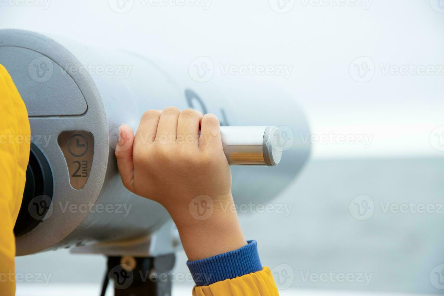 the boy looks through binoculars at the Baltic Sea. cool weather. photo