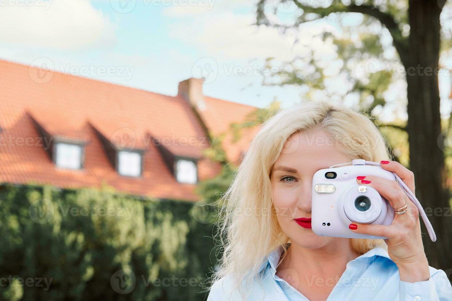 a woman on the street takes pictures on a polaroid. a warm summer day. Europe photo