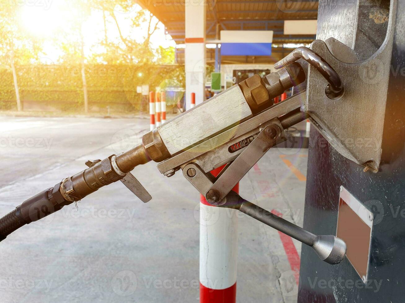 Closeup gas dispenser for automobile at gas station on blurry with sun flare and lens flare background. photo