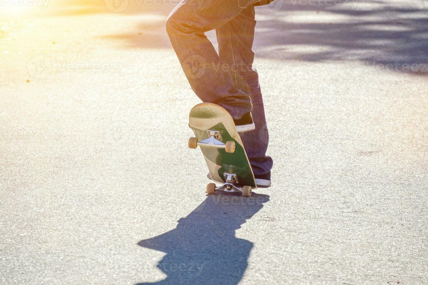 Closeup legs of teenager playing a skateboard on public park's road. photo