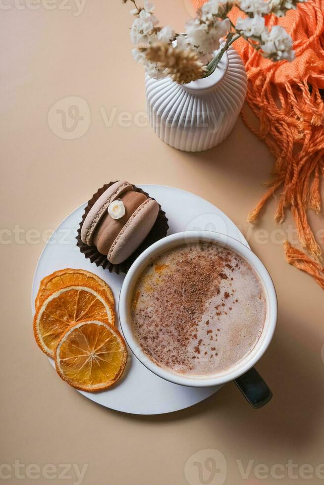 A cup of warm cocoa with a macaroon and cozy winter decor flat lay. Warm drink top view photo