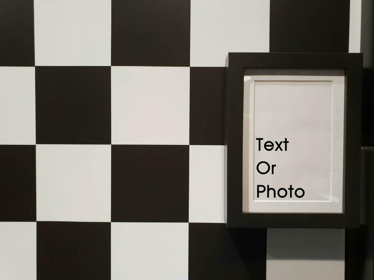 Closeup decorate black photo frame on black and white chessboard pattern wall in the toilet.