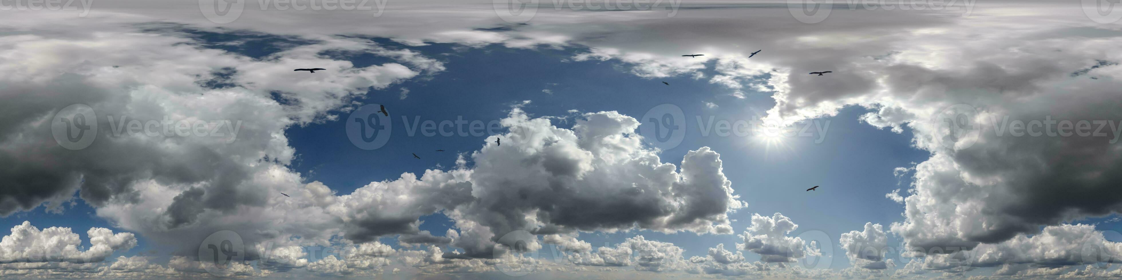 360 hdri panorama of blue overcast skydome with flock of birds in cumulus clouds, seamless sky panorama view with zenith for use in 3d graphics or game development or edit drone shot photo