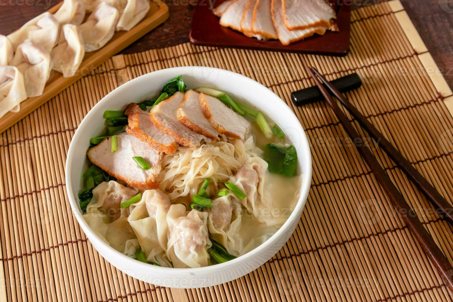 Closed up traditional Chinese food, wonton soup as stuffed dumpling with minced pork and slide roasted pork on wooden background photo