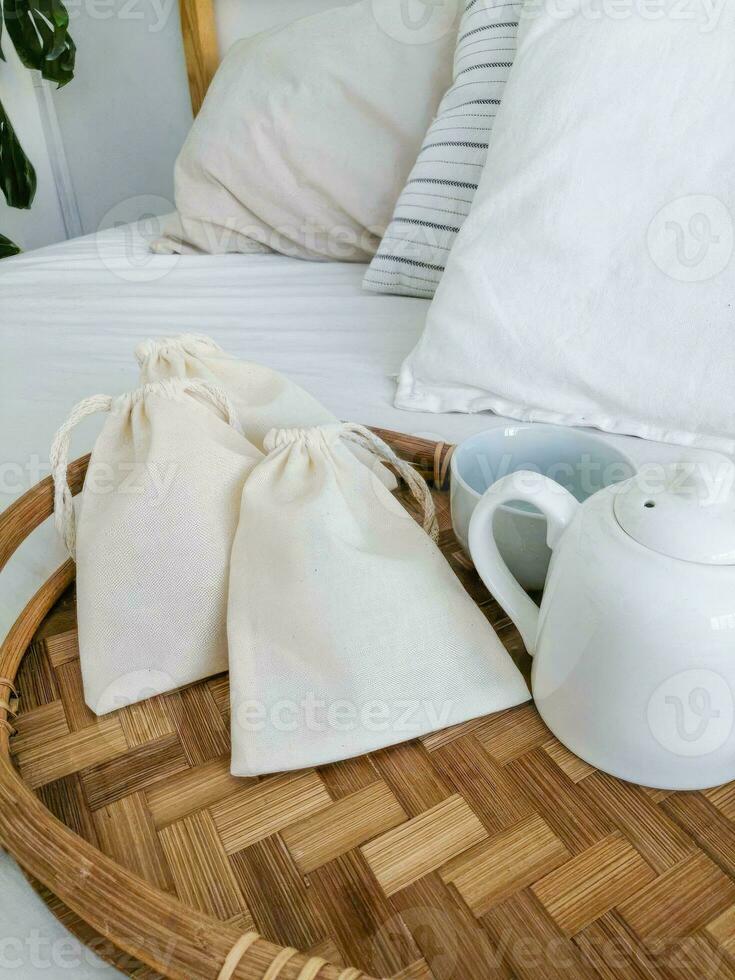 Cotton bags on a bamboo tray in a hotel room with a white bed photo