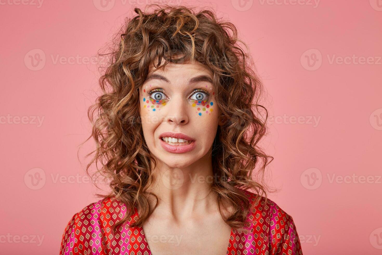 Close up photo of beautiful lady with big eyes opened feeling awkward, lifting eyebrows, saying oops, isolated over pink background