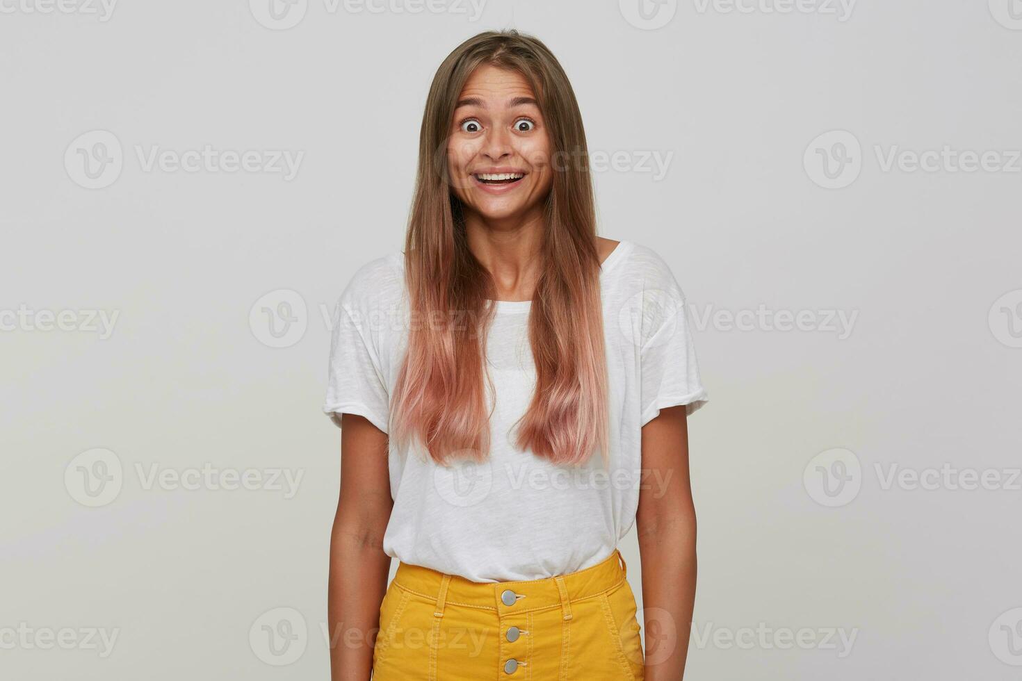 Suprised young pretty blonde woman with casual hairstyle rounding her brown eyes and raising amazedly eyebrows while looking at camera, isolated over white background photo