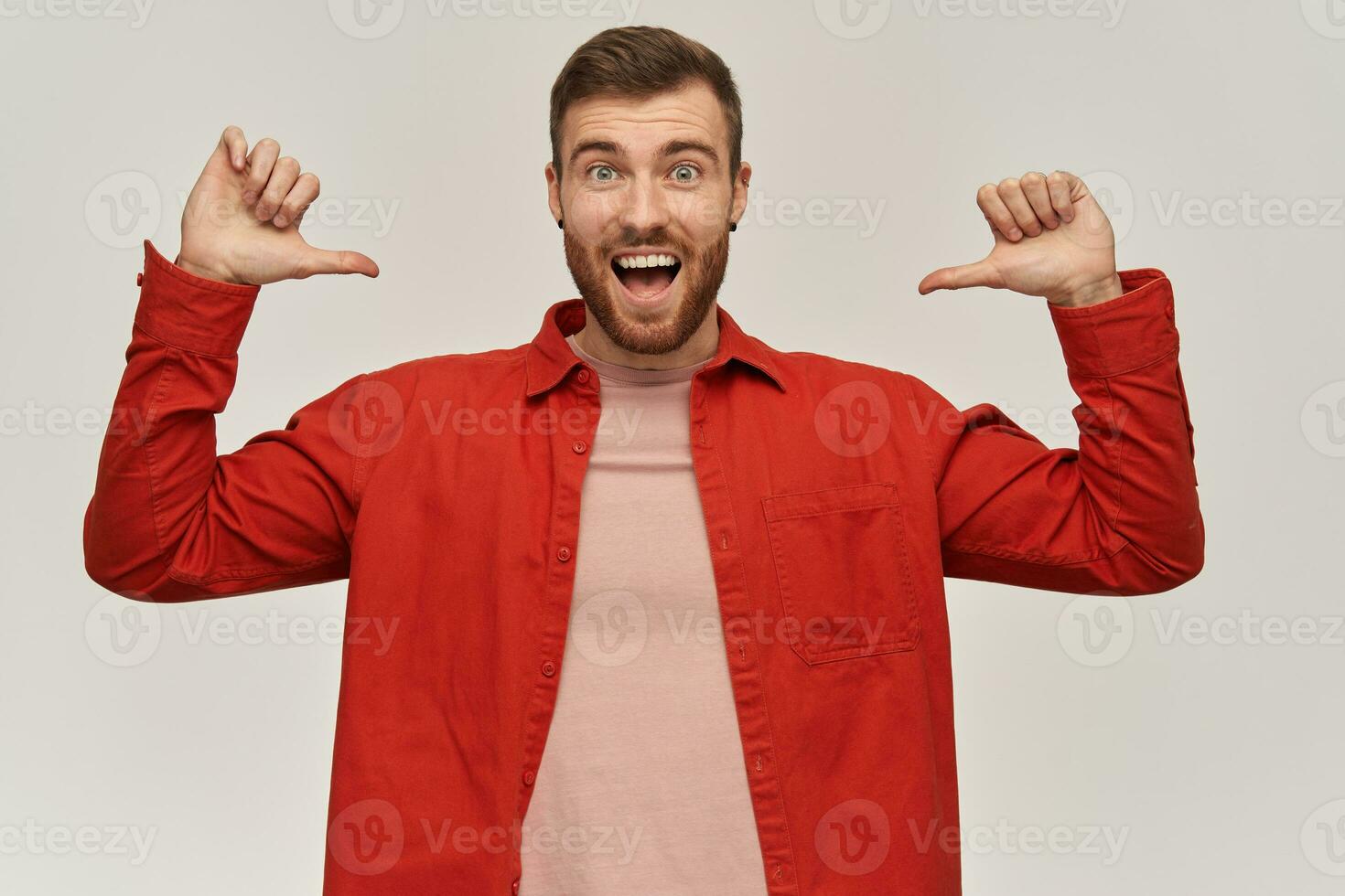 alegre emocionado joven barbado hombre en rojo camisa en pie y señalando a él mismo con dos ambos pulgares manos terminado blanco antecedentes foto