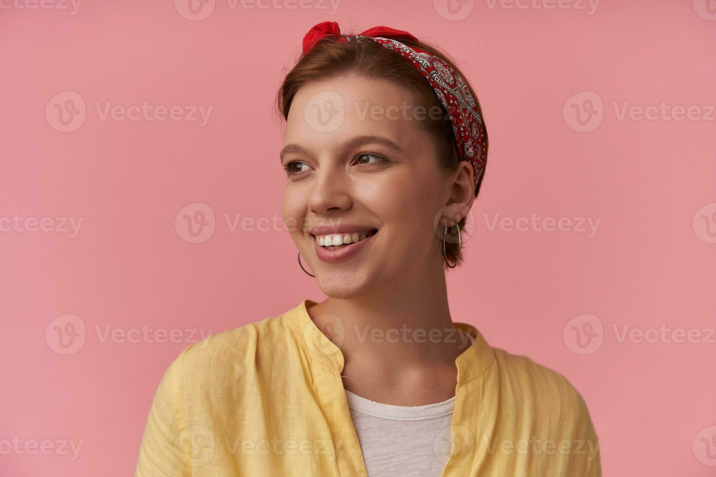 Image european brown haired charming woman 20s with natural makeup wearing stylish summer outfit white t-shirt and red bandana emotion smiling aside nice face glad and joyful posing against pink wall photo