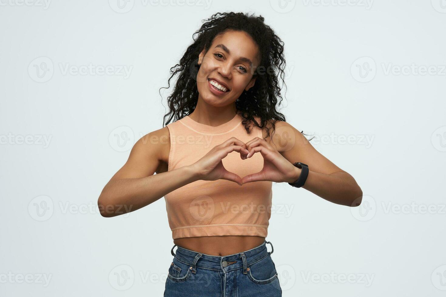 contento hermosa africano americano joven mujer siente amor y demostración corazón forma por manos aislado terminado blanco antecedentes foto