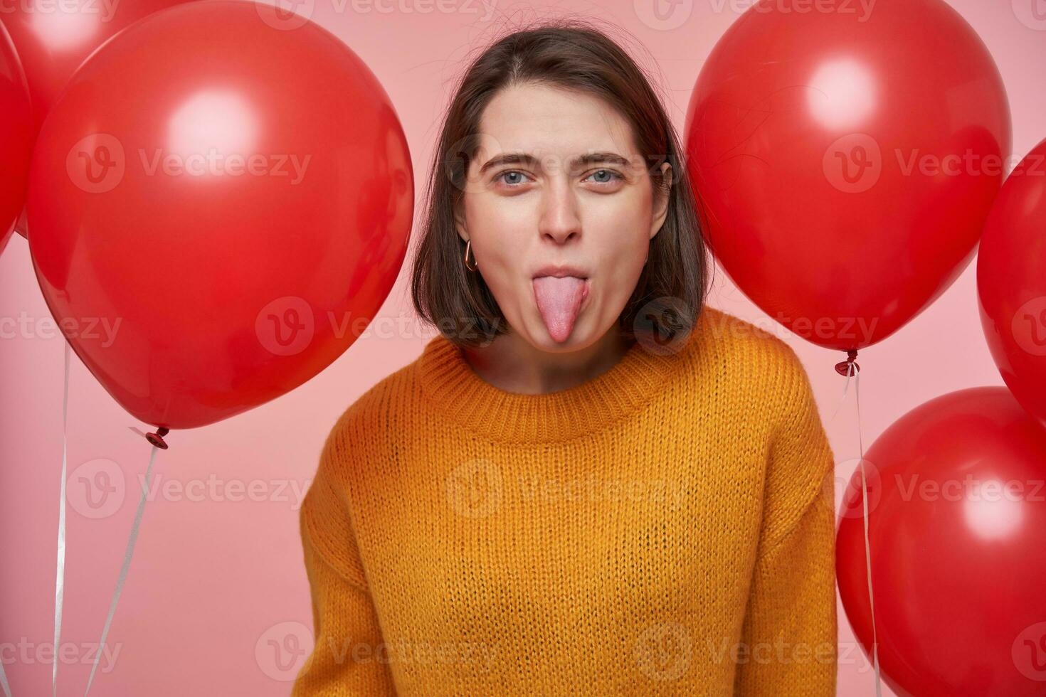 interior retrato de joven triste morena femenino, demostración su lengua. aislado terminado rosado antecedentes. foto