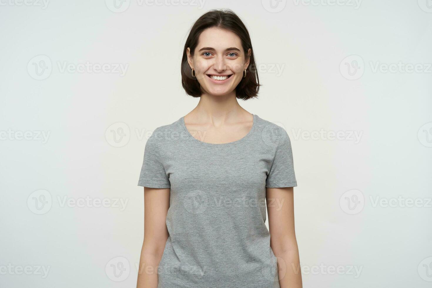 young brunette female student, looks directly into camera with brad smile on her face. Isolated over white background photo