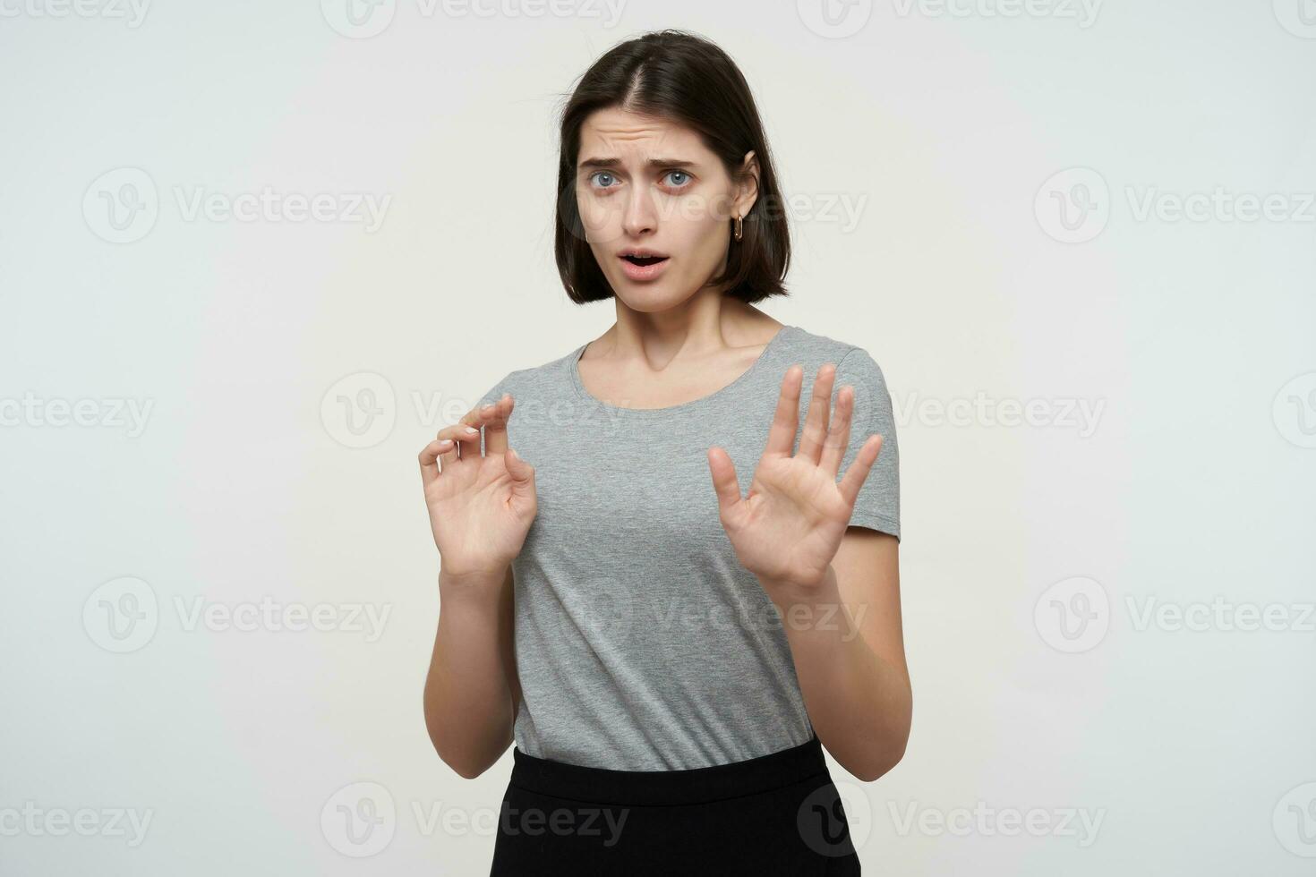 studio portrait of young brunette female shows stop gesture with both arms with sad unhappy facial expression photo