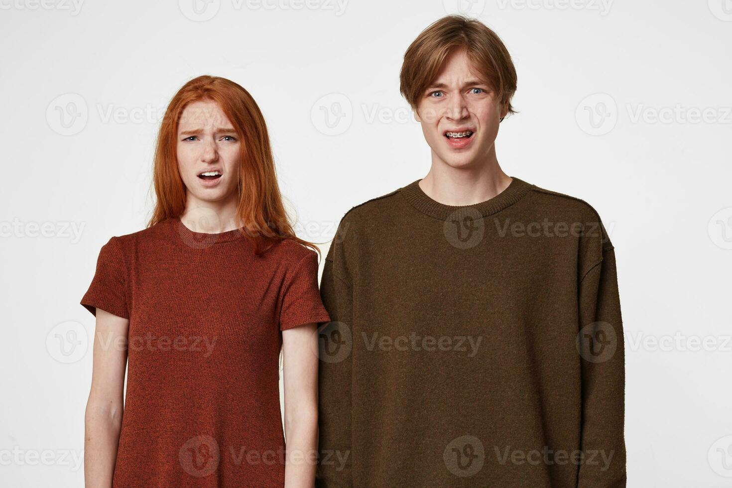 Indoor photo of young guys, boy and girl, look into the camera with an expression of disgust and frustration on their face. How could this happen What a mess, what to do about it