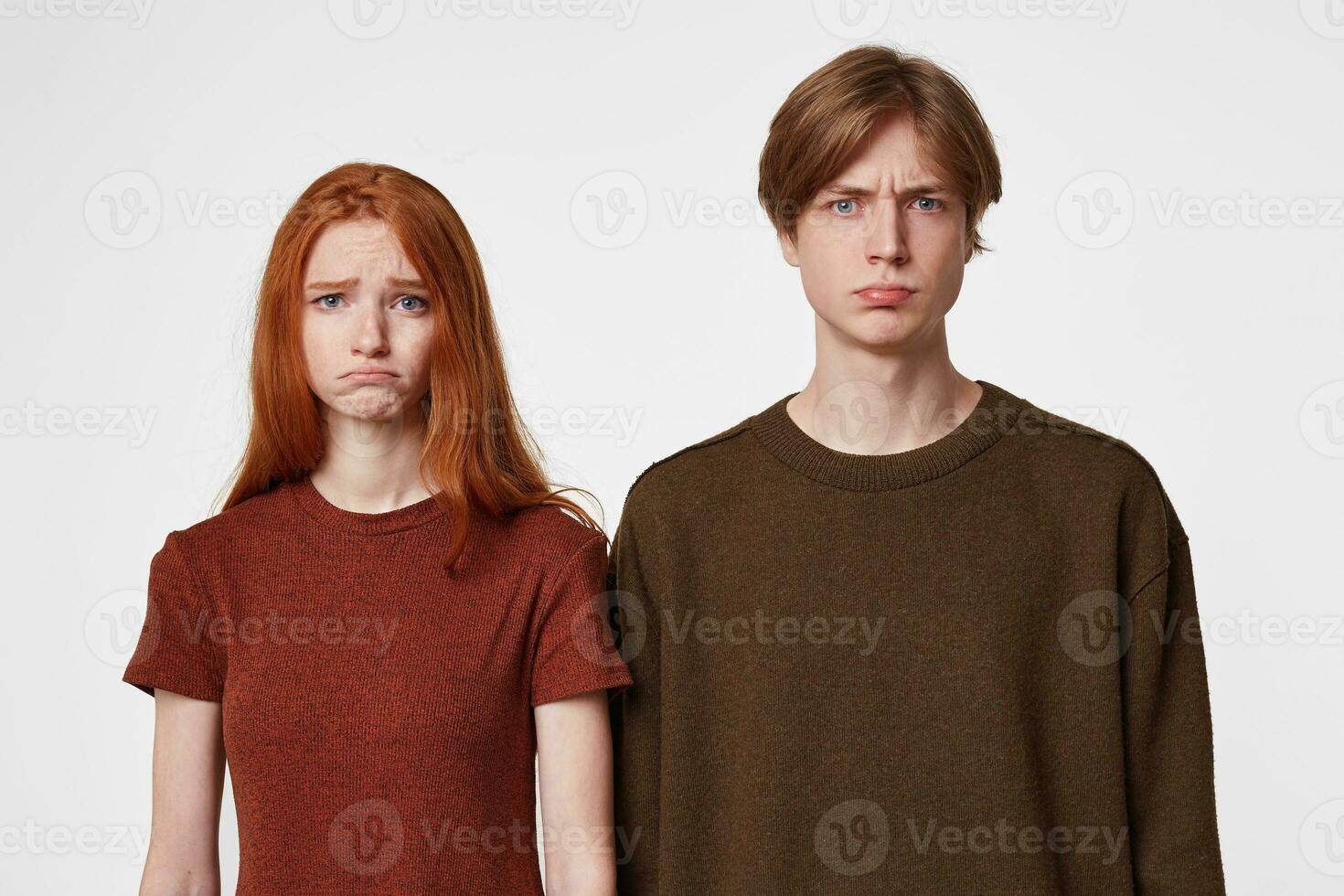 Offended upset little angry young guy and red hair girl isolated on white background looking directly into the camera, dressed casual. photo