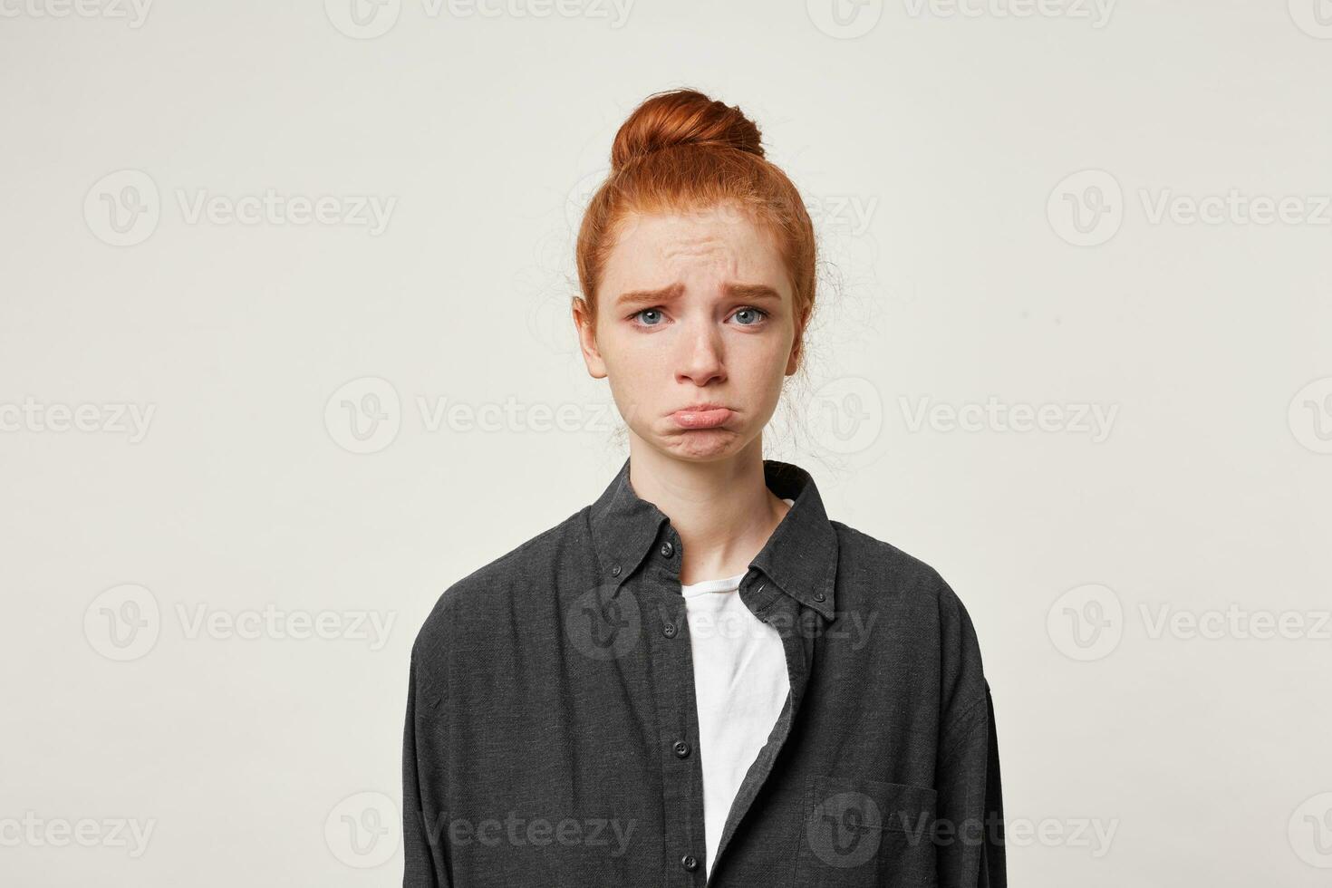 Close up of young sad red-haired girl, she is very upset, frowns eyebrows, lowered her lower lip, looks lamentable. The girl is offended because she did not get a gift. photo