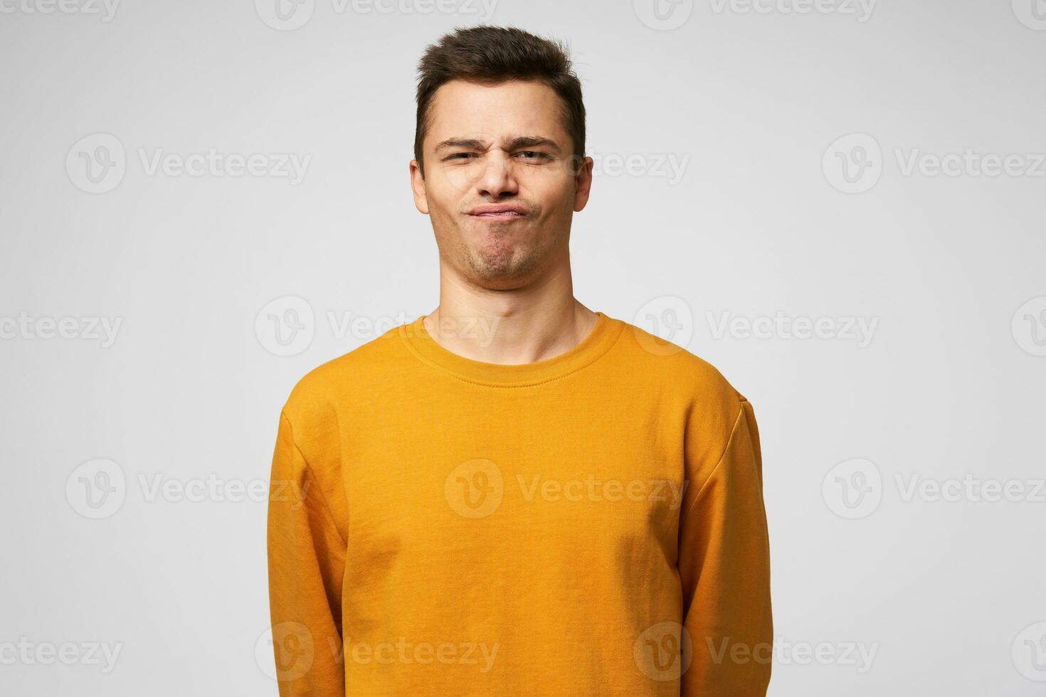 Studio shot of a young guy standing confident, chin up, on the face expression of a success, winning, show class, winner, pleased enjoying himself, isolated over white background photo