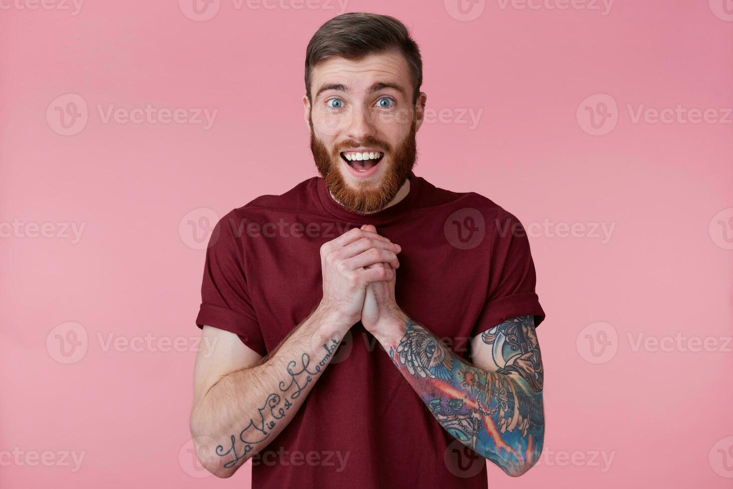 cerca arriba de contento hermoso barbado joven hombre con tatuado mano, Sierra alguna cosa linda y sonriente, mirando a cámara aislado terminado rosado antecedentes. foto