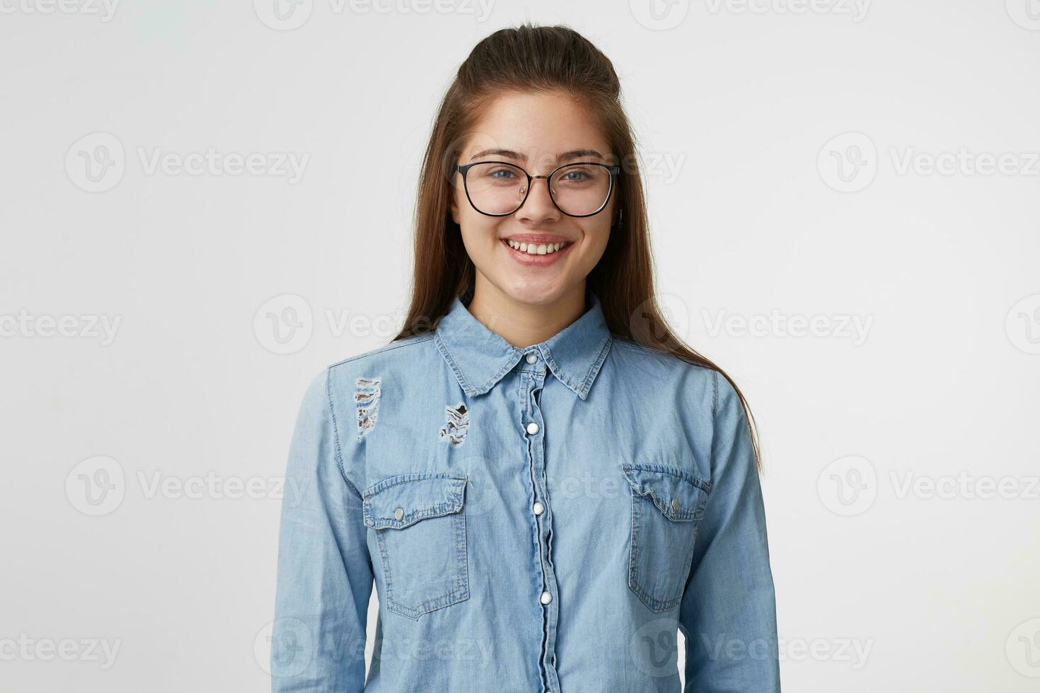 retrato de muy linda y atractivo niña en lentes sonriente, vestido en un de moda mezclilla camisa, aislado en un blanco antecedentes foto