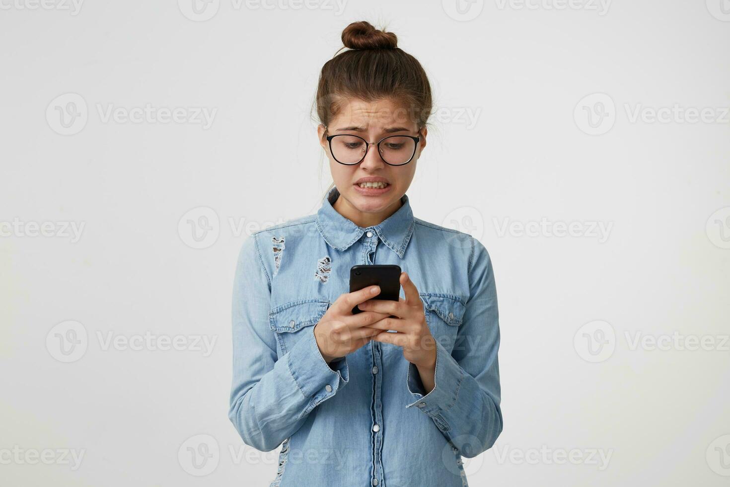 Girl read the message from which she fell into a panic, gritted her teeth, she is nervous, trying to correct the situation, wants to solve the problem quickly isolated on a white background. photo