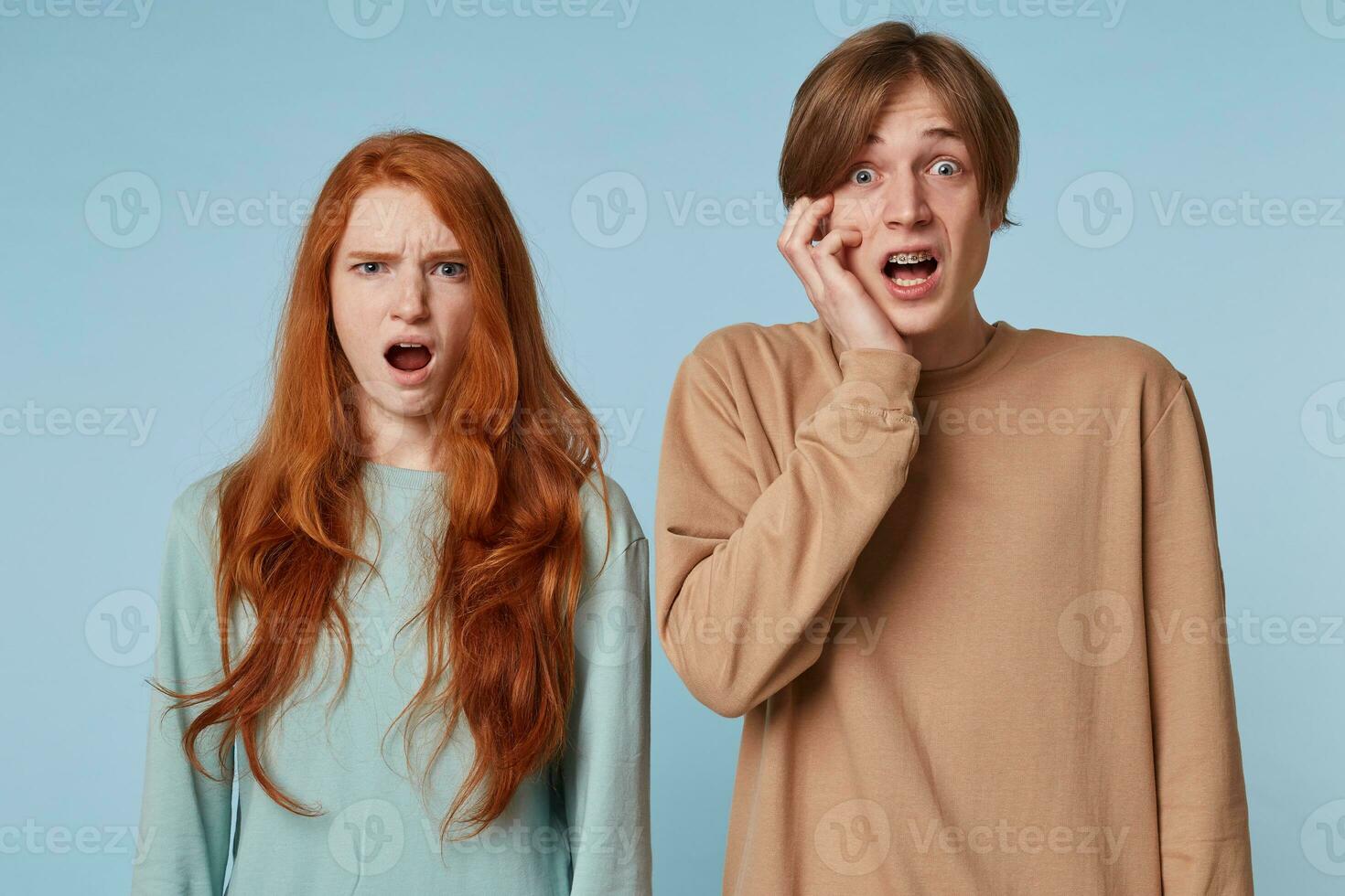 Close up couple, looking at the camera with stunned offended shocked facial expression as if they saw something inappropriate immoral beyond the limits of propriety,isolated on a blue background photo