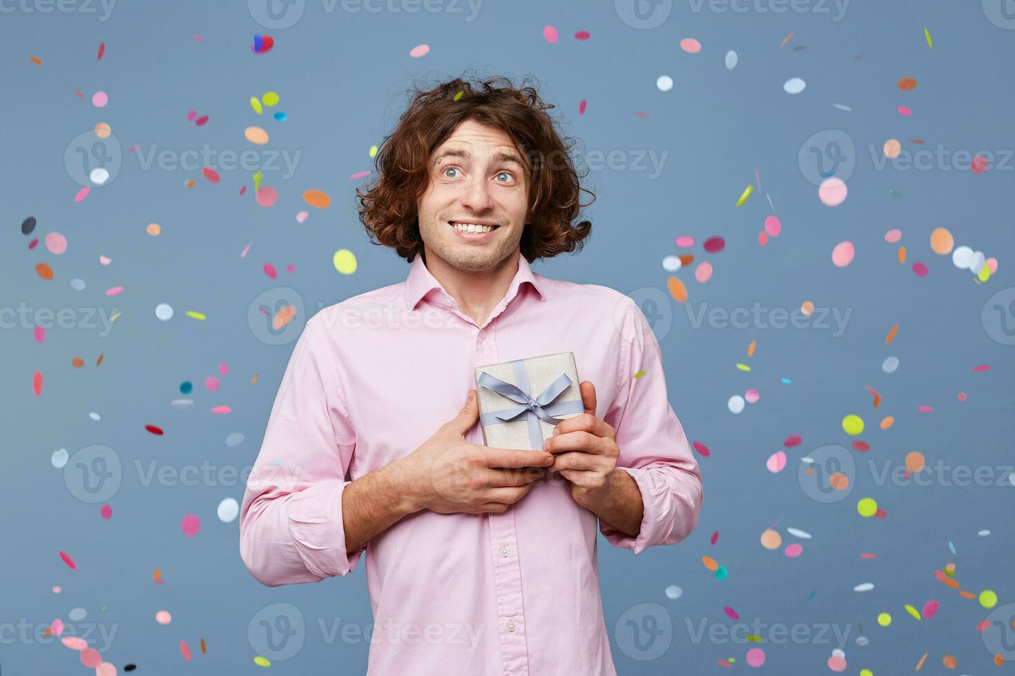 Portrait of the birthday man takes photos with a gift box, holds it in his hands, looks away, on his face an expression of bewilderment, did not expect to receive such a small gift