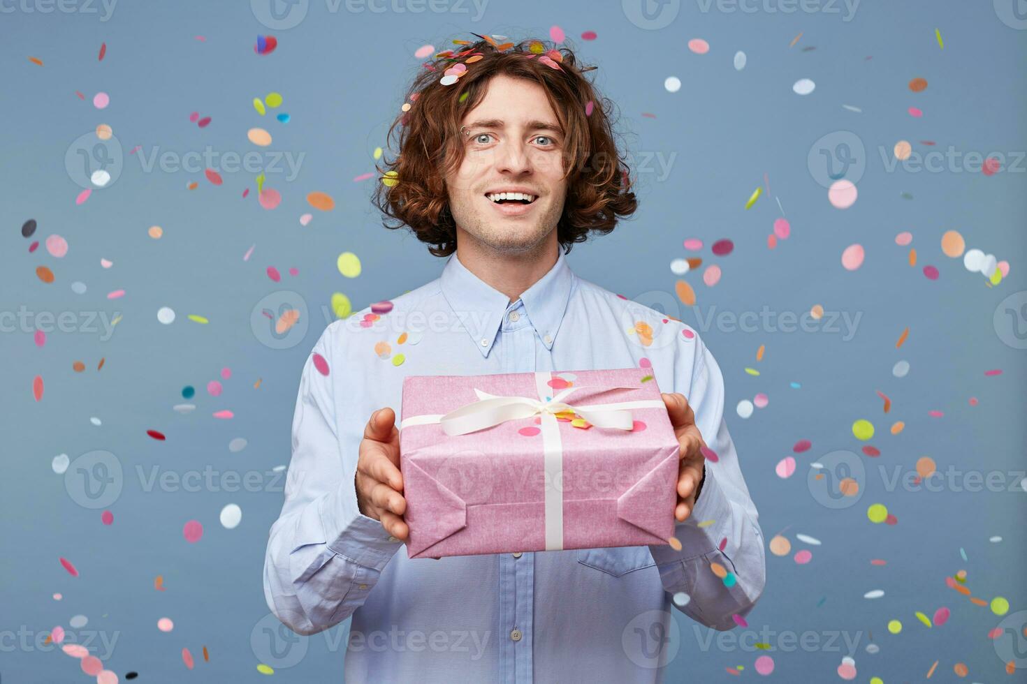 A man came for a holiday, giving a gift, in his hands a pink box tied with a white ribbon, smiling and ready to say many warm words to a birthday man. photo