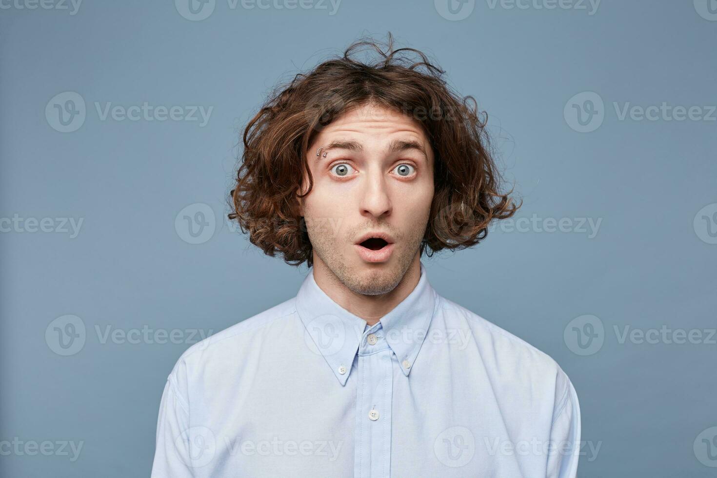 Indoor shot of amazed excited man doesnt believe his success, keeps mouth wide opened, stares at camera, says omg or wow. Pleasant surprised male photo
