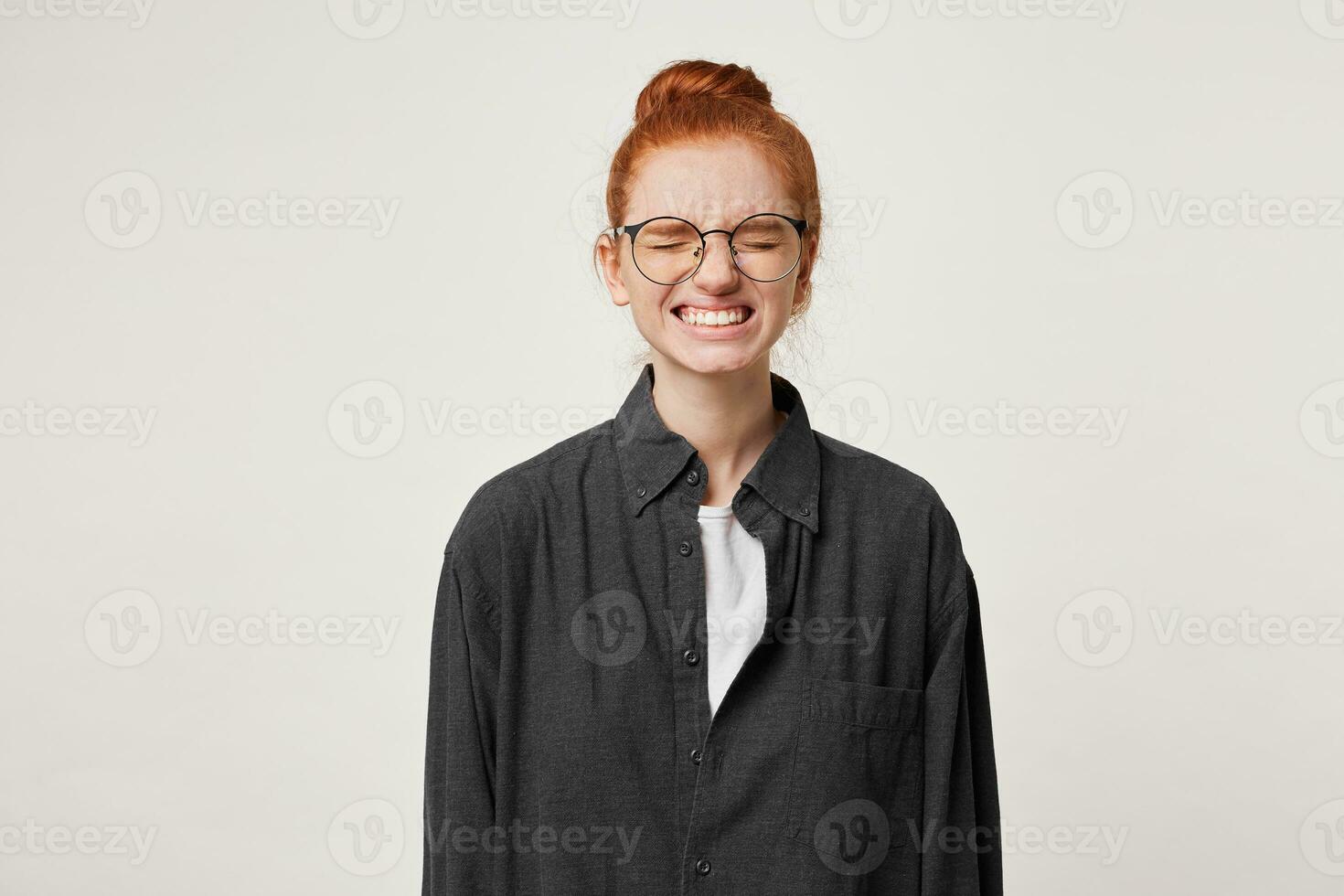 Red-haired girl student wearing glasses, eyes closed, face grimace as if she forgot to do something necessary, now she remembered something important, deeply regrets that she didn't make in time photo