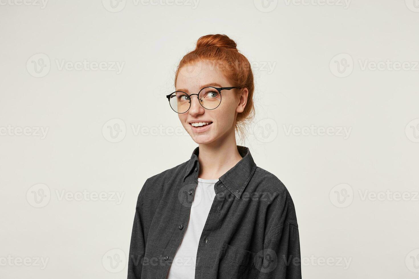 Headshot of an attractive charming female with red hair, dreamily looks away, imagine something pleasant, nicely smiling, over white studio background photo