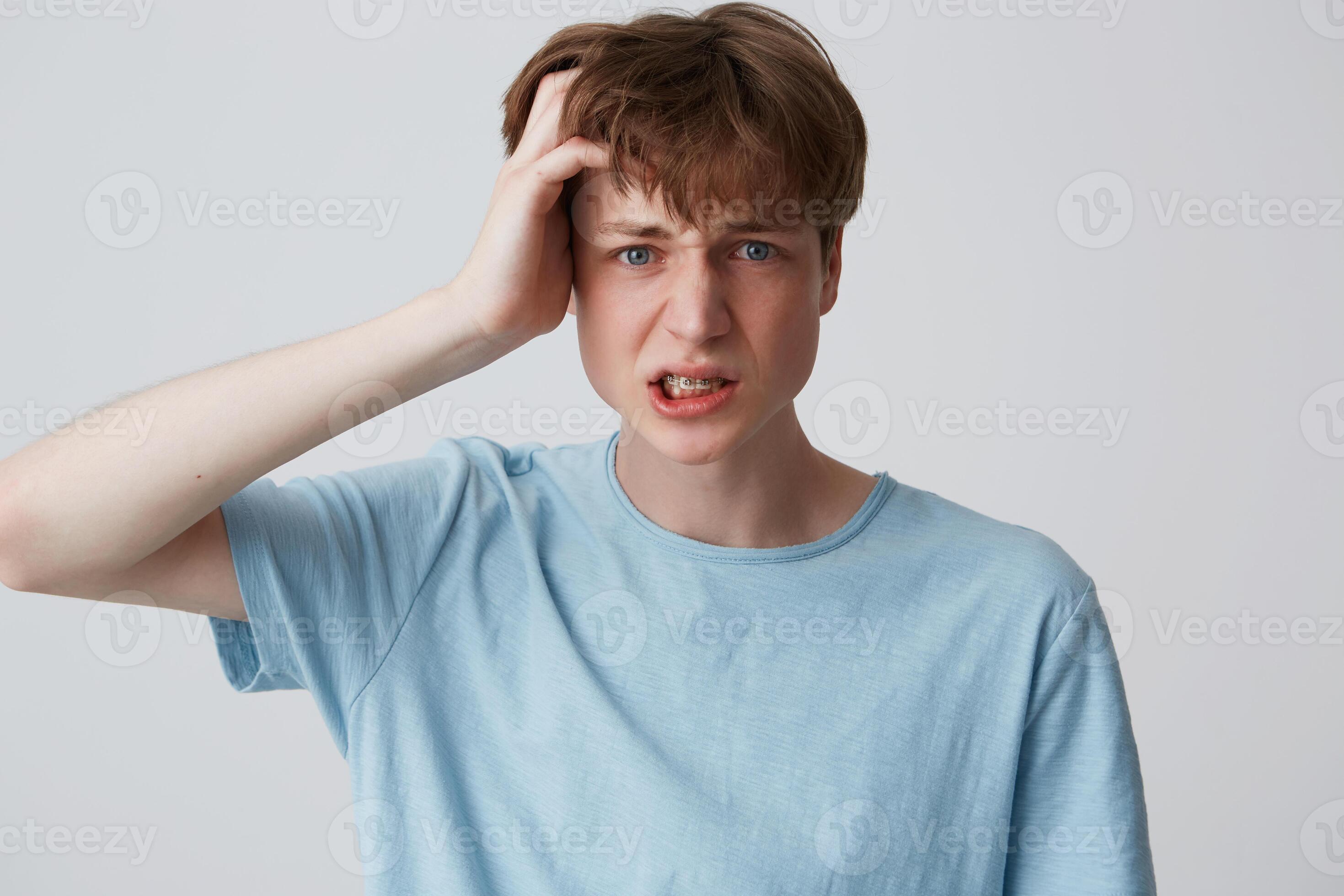 Portrait of stressed displeased young man with braces on teeth wears