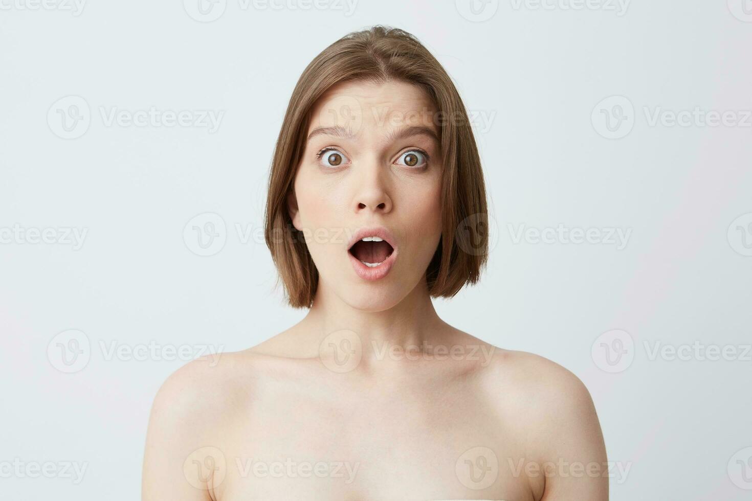 Close up shot of astonished cute young woman with perfect healthy skin looks shoked and surprised isolated over white background Feels excited after shower photo
