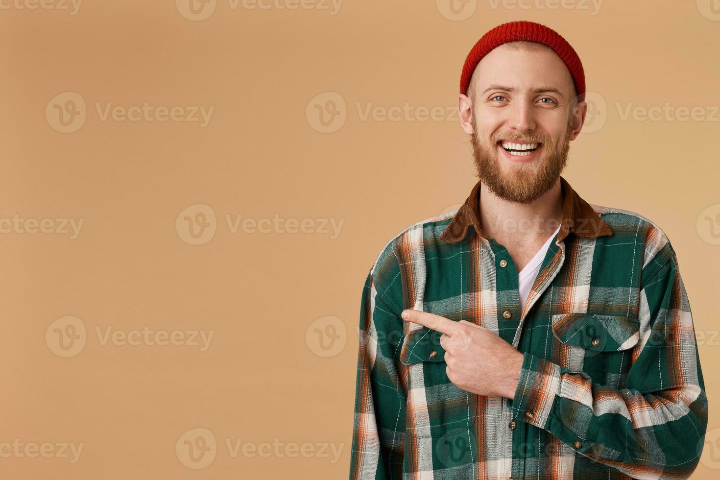 A happy contented person advertises a great product, which he uses himself and was satisfied with the result. A cute guy smiles and laughs,points with index finger to the left to an empty space. photo