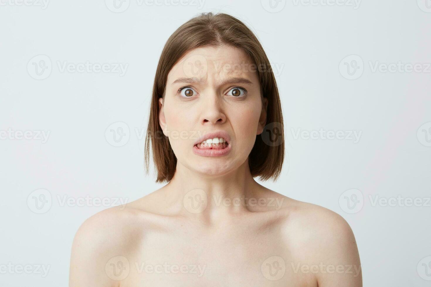 Horizontal shot of sad worried young woman with perfect skin after applying mask or cream after shower feels stressed and have problems isolated over white backgound photo