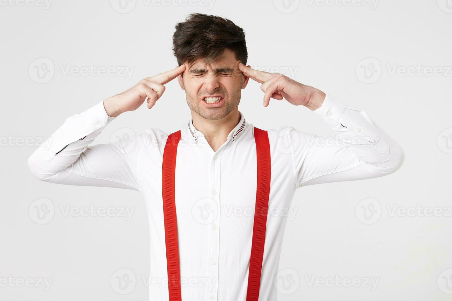 Portrait of young man isolated on white background, suffering from severe headache, pressing fingers to temples, closing eyes photo