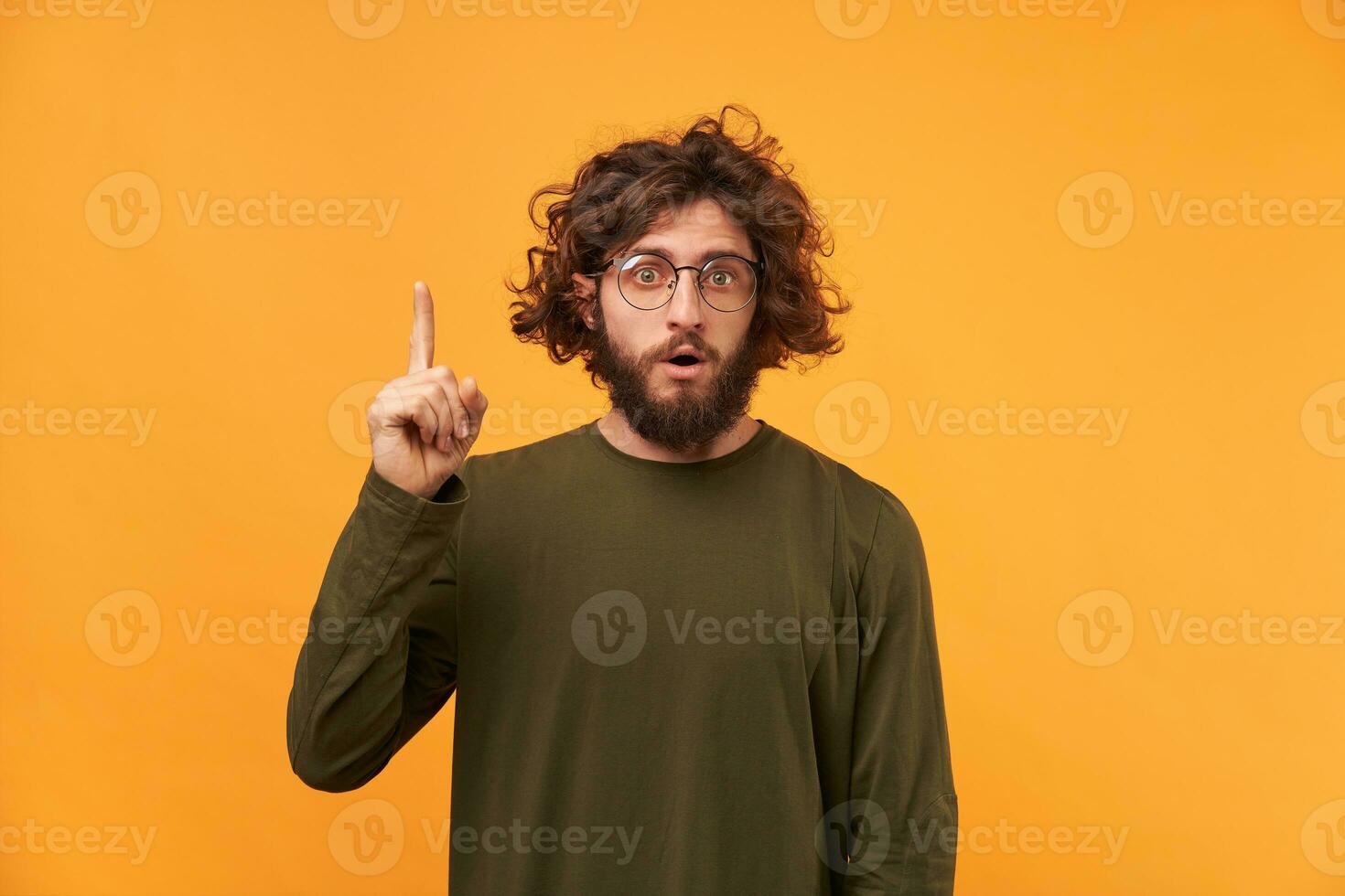 The student came up with a solution to the problem isolated over yellow background. Curly-hair bearded guy with glasses showing his index finger upwards has the idea, thought inspiration photo